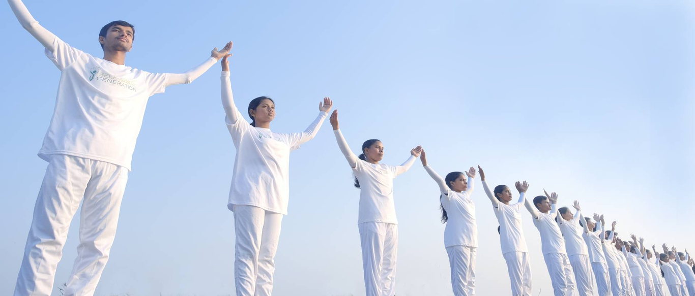 A long diagonal line of young people dressed in white, arms raised with palms touching, receding into a clear morning sky.